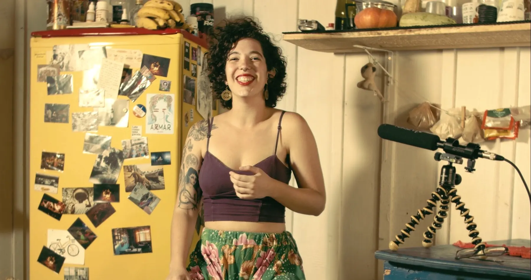 Bianca Amante sorri na cozinha de paredes de madeira durante a live session Ao Vivo na Cozinha, com microfone em tripé