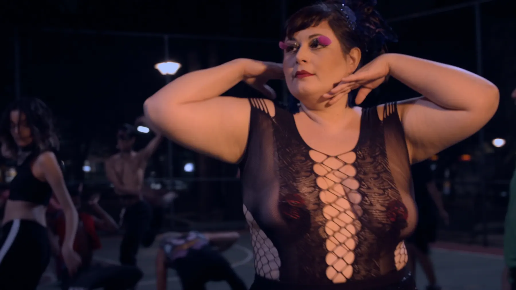 Dançarina de body de renda faz pose de vogue numa quadra pública em cena do documentário Basquete das Excluídas