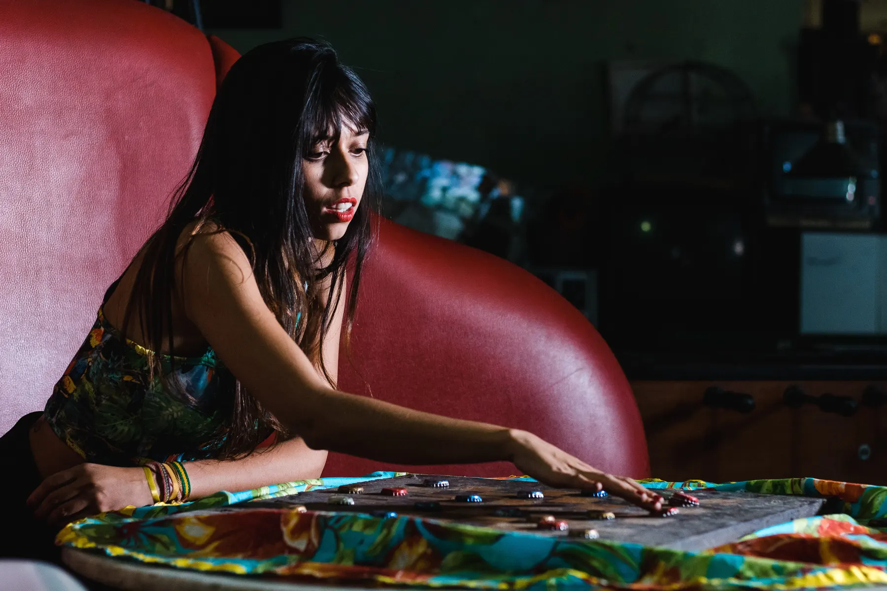 Layse Rodrigues, vocalista da Farofa Tropikal, debruçada num sofá vermelho no making of do clipe Desdenhas