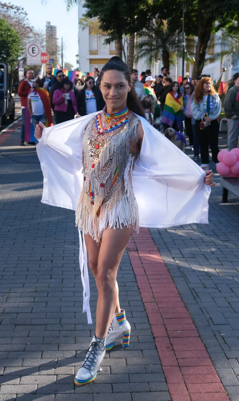 A drag queen in a white cape and embroidered bodysuit struts before the march.