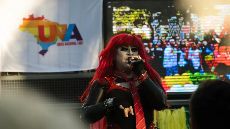 A red-wigged drag queen sings on the float.