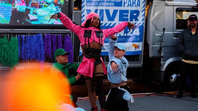 A dancer in pink and dancers performing a routine by the float.