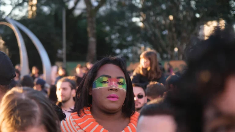 A face painted in rainbow colors in the crowd.