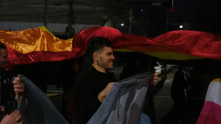 A huge flag crosses the crowd in the dark.