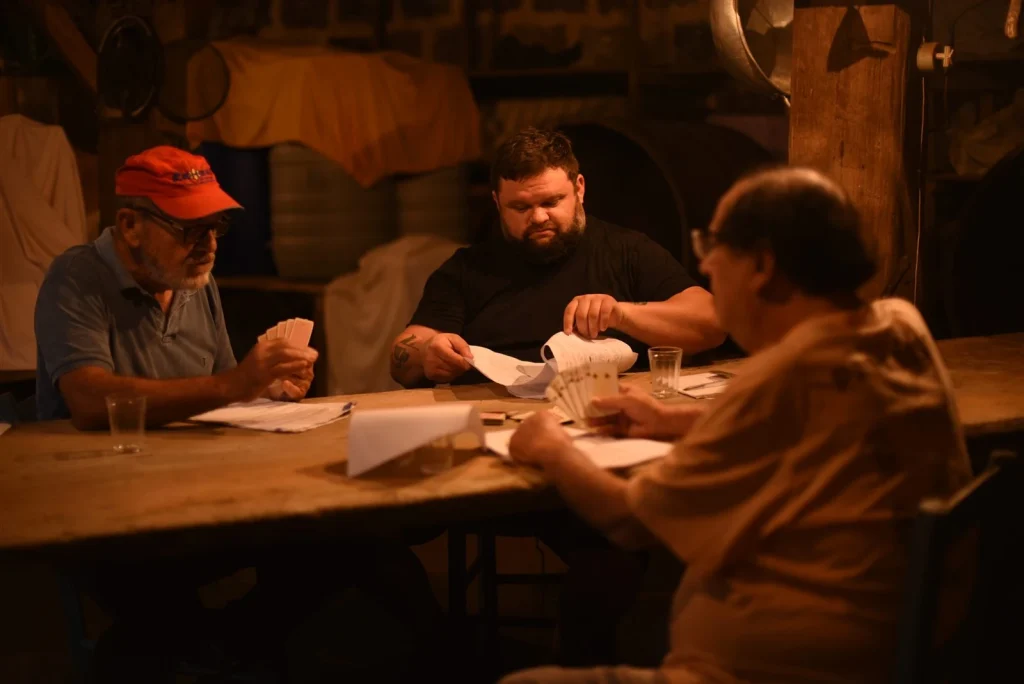 O que é de César: amigos jogam cartas à luz quente de um galpão