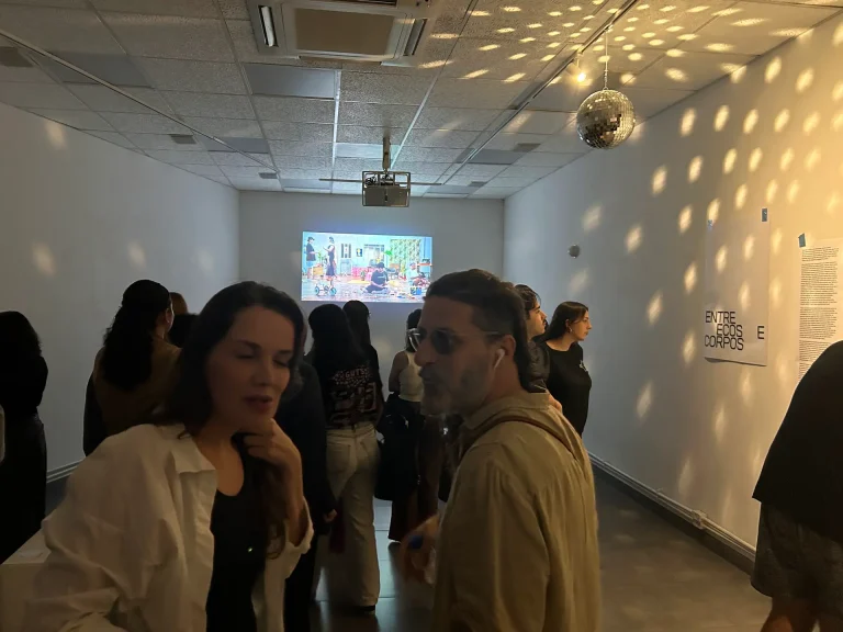 Globo espelhado espalha pontos de luz pela sala enquanto o público assiste à projeção