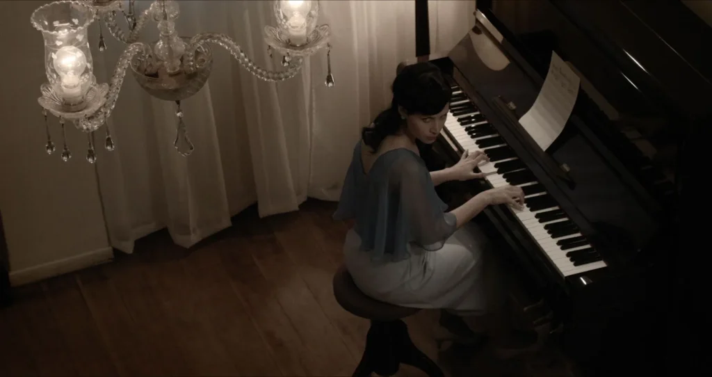 Preto Pálido: Analu ao piano, sob um lustre de cristal