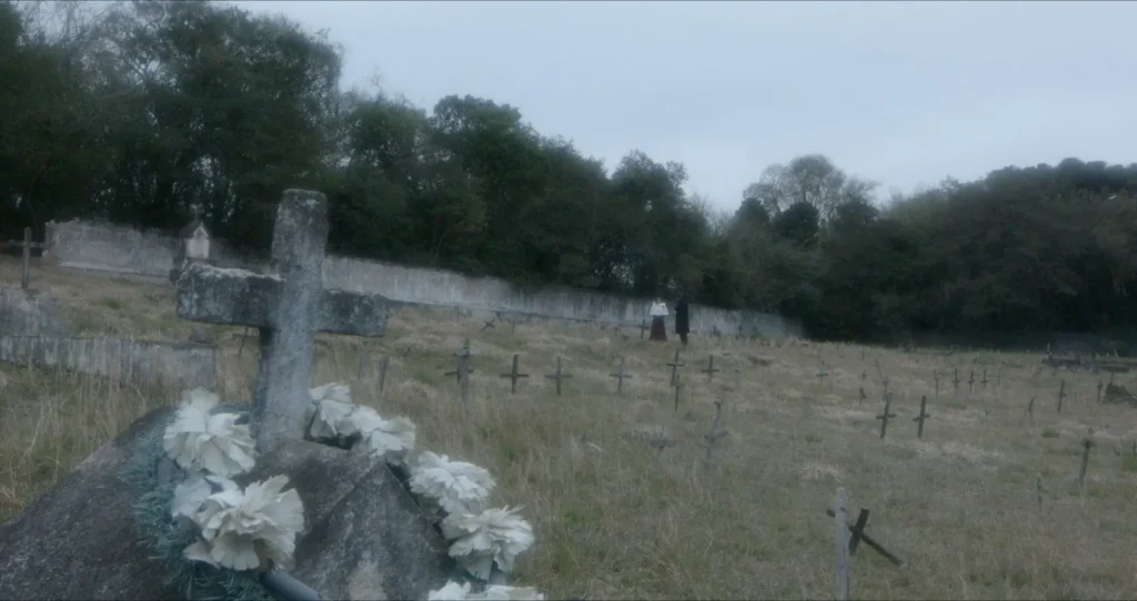 Preto Pálido: túmulo com cruz e flores brancas num cemitério de campo