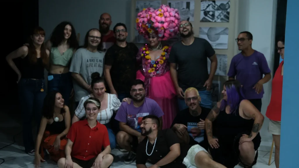 Foto de grupo do público do Tela Expandida, com a drag ao centro, na Casa da Cultura Rogério Sganzerla